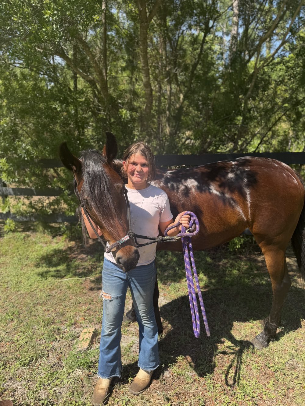 A young woman with a bay horse on a sandy path at The Refuge